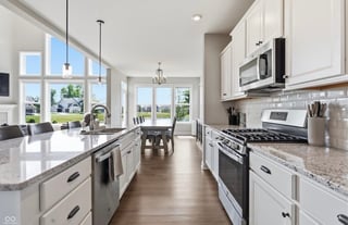 Modern kitchen with white cabinets, stainless steel appliances, granite countertops, and view to dining area with large windows overlooking exterior