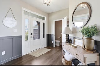 Modern farmhouse entryway with white French doors, wooden console table with round mirror, potted plants, and neutral decor