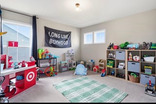 Colorful playroom with toy storage shelves, red play kitchen, Long Live Boyhood banner, and green checkered mat