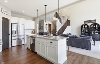 Modern open-concept kitchen and living room with white cabinetry, stainless steel appliances, island, and wooden flooring