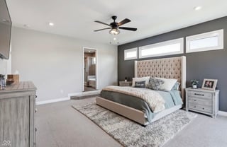 Modern master bedroom with tufted headboard, ceiling fan, neutral gray and white decor, and white nightstands
