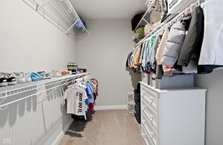 Organized closet with white wire shelving, white dresser drawers, hanging clothes on rod, and storage items on shelves