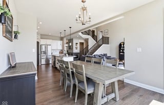 Modern open-concept home interior with dining table, kitchen, and staircase visible in background