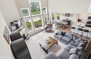 Overhead view of a modern open-concept living room with gray furniture, large windows, and a workspace area