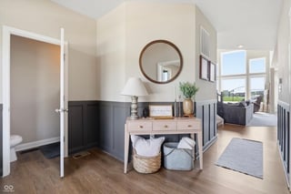 Modern bathroom interior with vanity, round mirror, woven basket storage, and black lower wall paneling on wooden floor